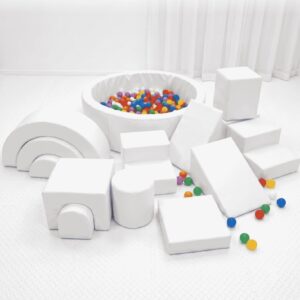 A luxury all-white soft play setup featuring a chic ball pit, white foam climbing blocks, and a mini slide on a clean white play mat