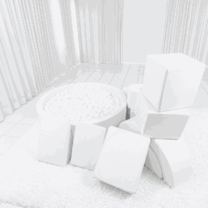 A luxury all-white soft play setup featuring a chic ball pit, white foam climbing blocks, and a mini slide on a clean white play mat